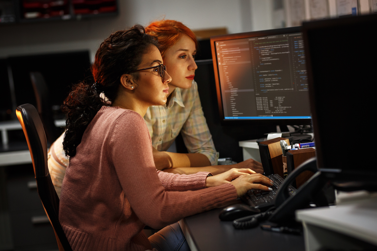 a red headed woman and a brunette at a computer
